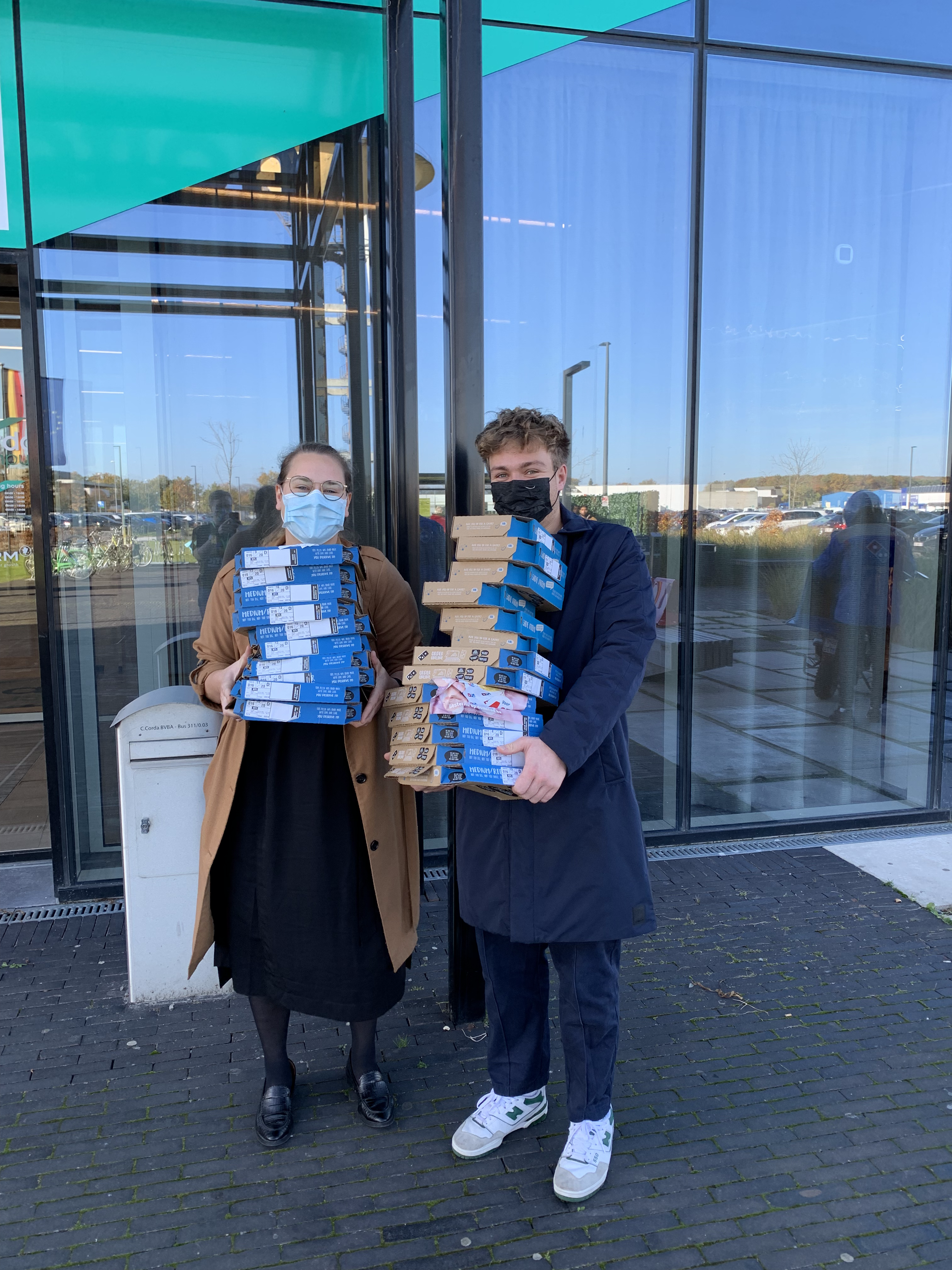 Photo of two people with large stacks of pizza outside the conference centre