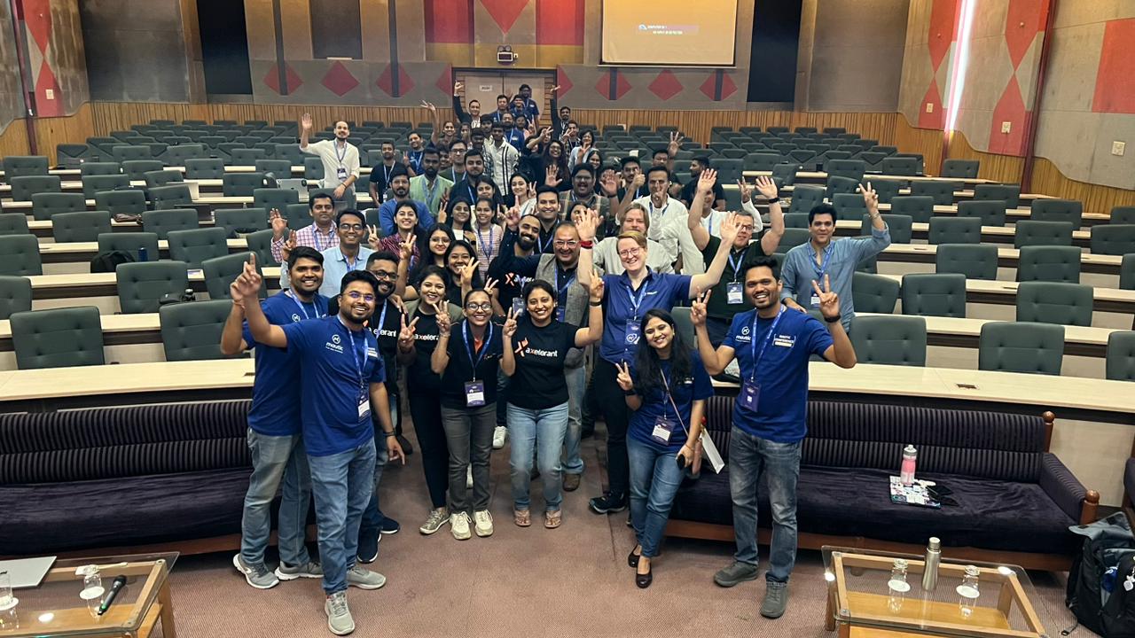 Photo of the auditorium at Mautic Conference India with the team and attendees standing smiling to the camera with their arms raised in the air.