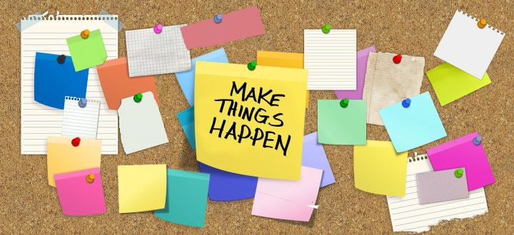 Image of cork board with multiple coloured sticky notes and a large yellow note in the centre with 'Make Things Happen' written in black ink.