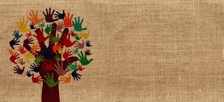 Painting of a tree with leaves of multiple colour handprints on a hessian canvas background
