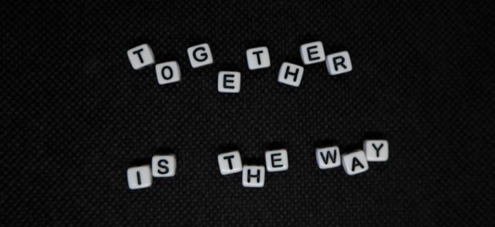 A black background with 'Together is the way' displayed with each letter being an individual white dice with black lettering