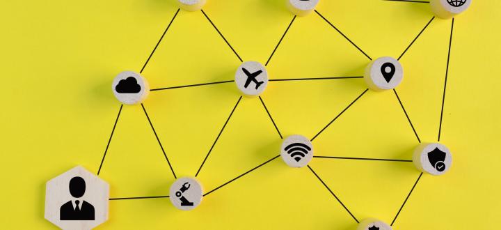 Illustration of lots of things associated with a contact (plane, wifi symbol, other people, location, web, security shield, settings, reports) connected with a black line to the user and each other. Yellow background, the things are all wooden circles with black symbols.