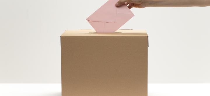 a hand putting a pink envelope into a brown box