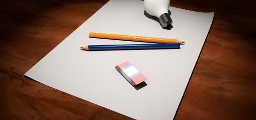 Photo of paper with two pencils, an eraser and a lightbulb on a wooden surface