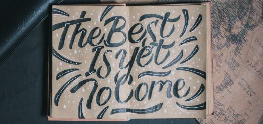 Photo of a drawing on two pages of a notebook which says 'the best is yet to come' with the pen beneath the notebook and another to the side.
