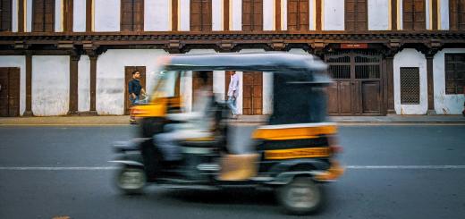 Photo of a motion-blurred autorickshaw driving down a street in India